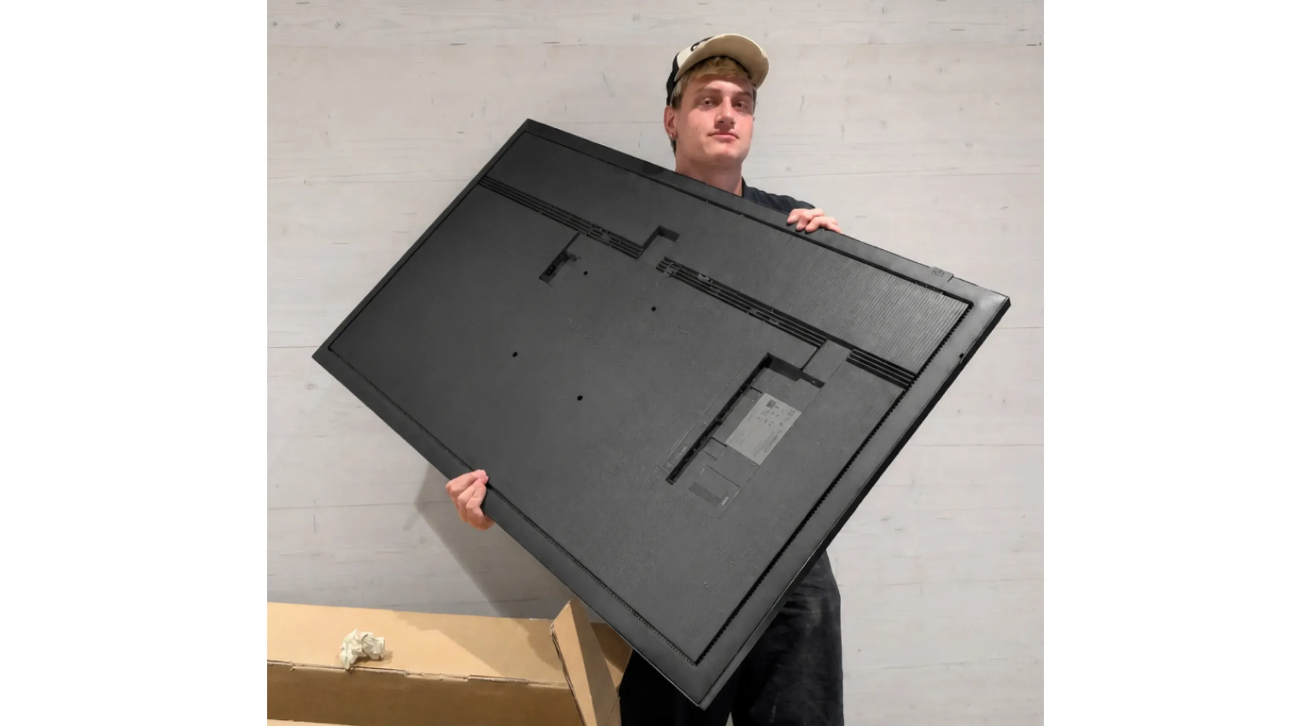 Lorenzo hält einen Digital Signage Bildschirm in den Händen.