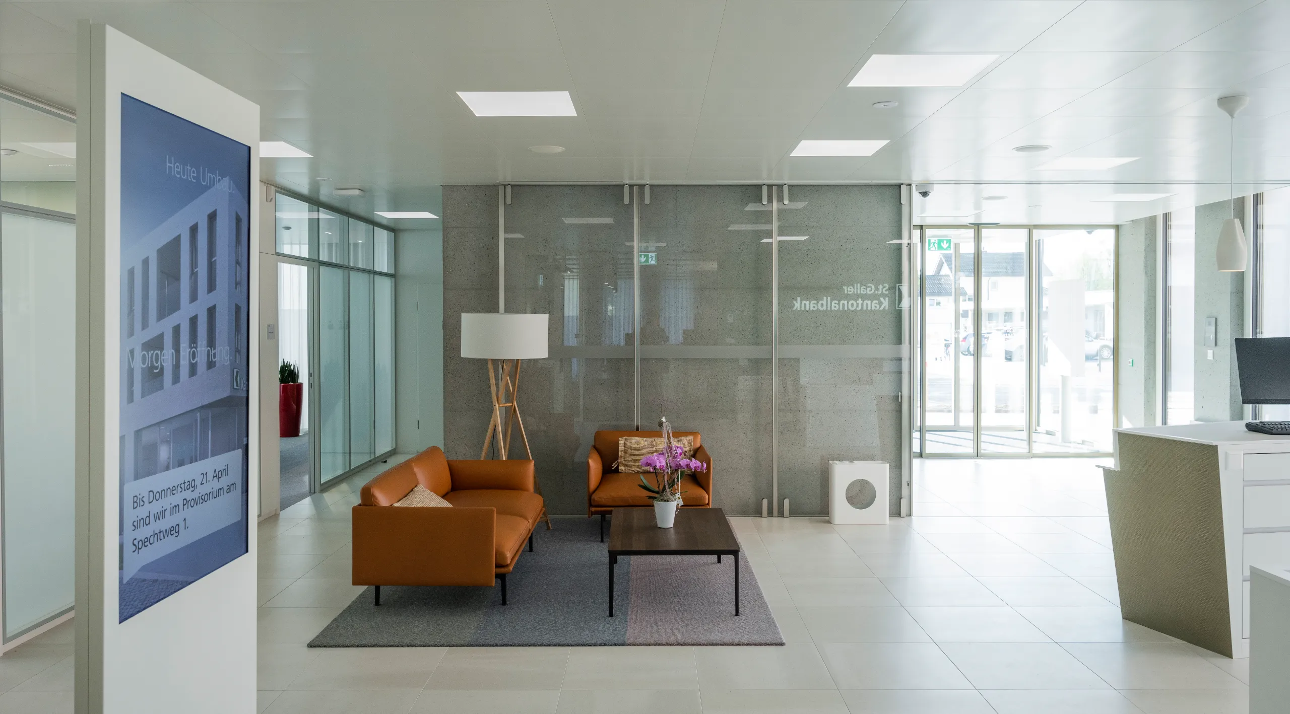 Empfangsbereich einer SGKB-Filiale mit grossformatigem jls Digital Signage Screen für automatisierte Kundeninformation und standortspezifische Filialkommunikation.