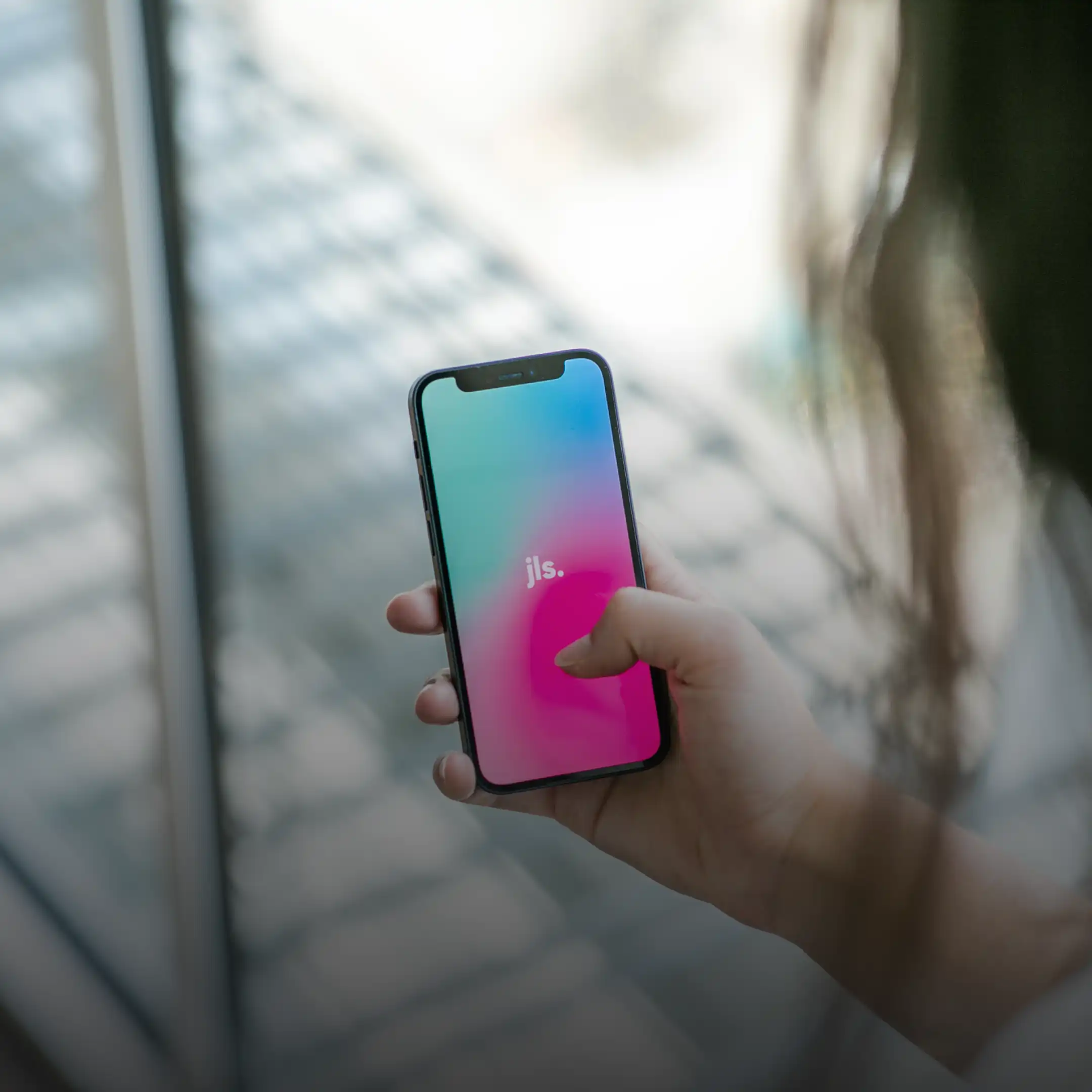 Person hält ein Smartphone mit farbigem Display – symbolisiert digitale Interaktion und mobile App Lösungen einer Mobile App Agentur.