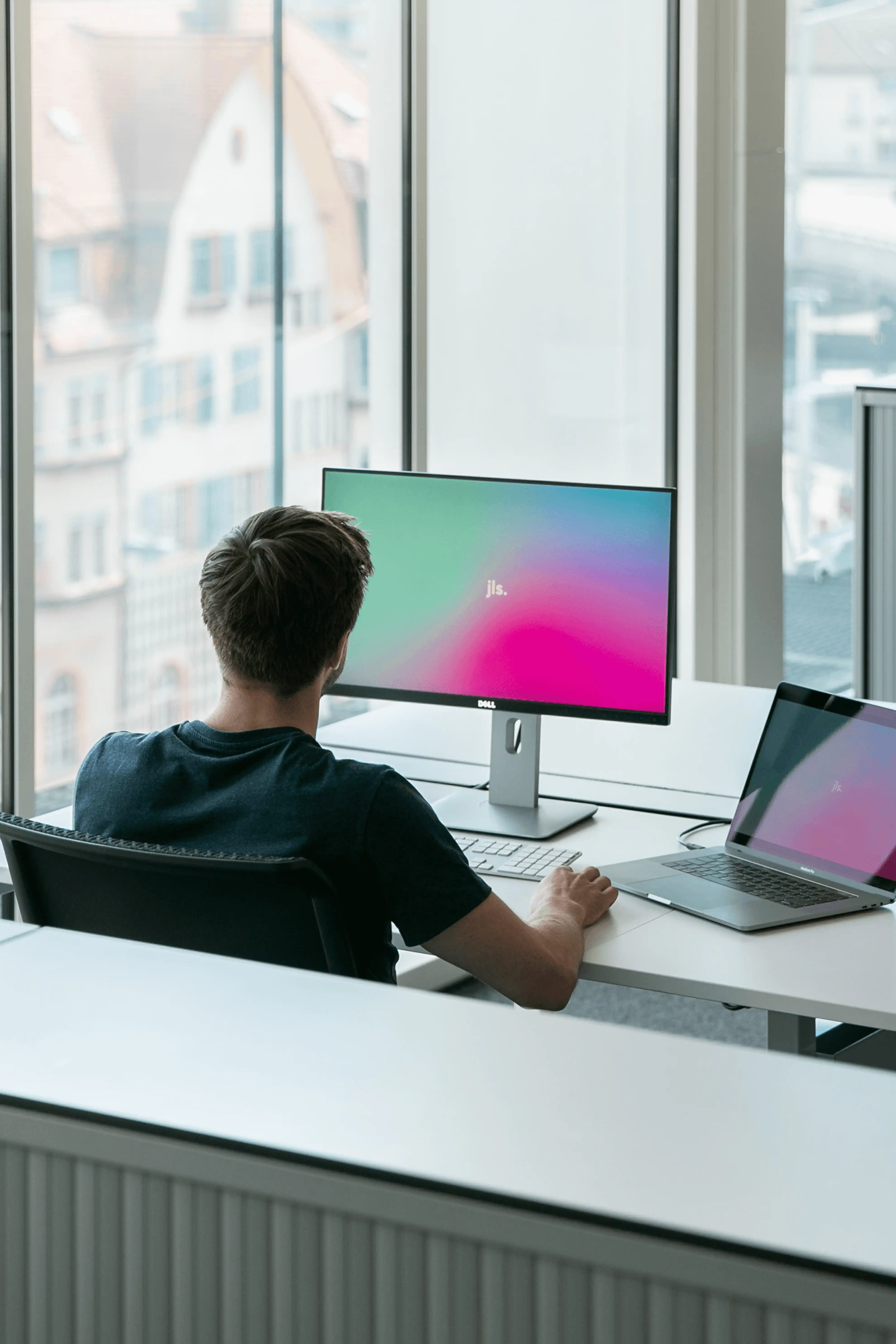 Mann sitzt an Arbeitsplatz mit Laptop und externem Bildschirm