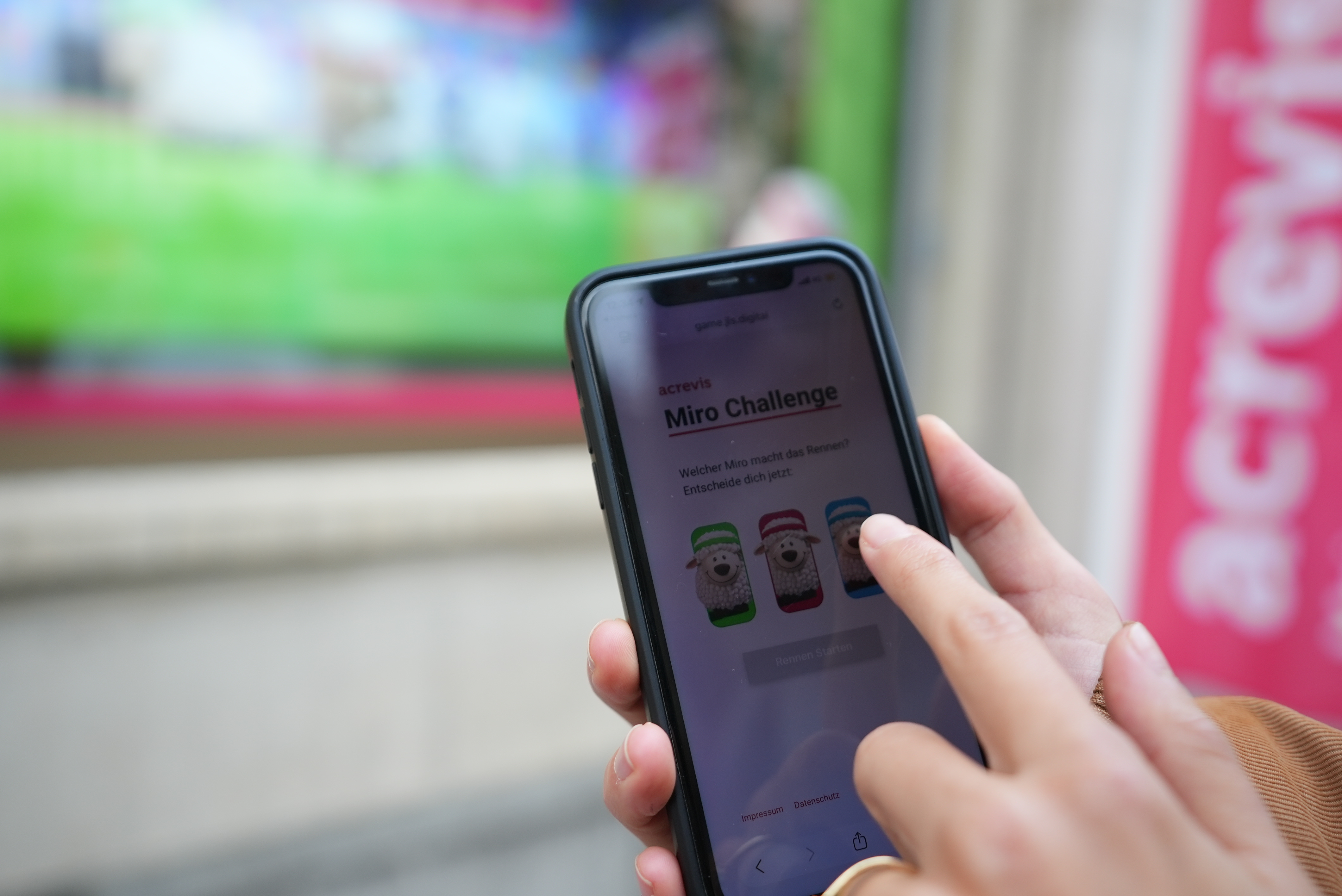 Gamification Umsetzung von jls: Frau und Kind scannen einen QR-Code und starten das acrevis Miro-Schaf-Rennen am Screen.