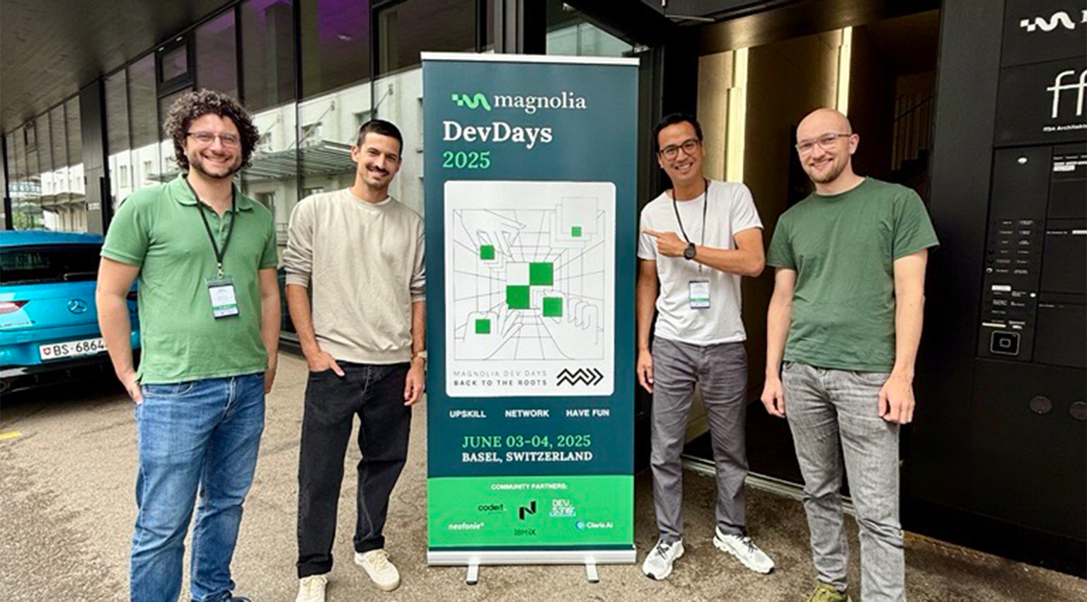 Zwei jls-Mitarbeiter vor dem Banner der Magnolia DevDays 2025 in Basel