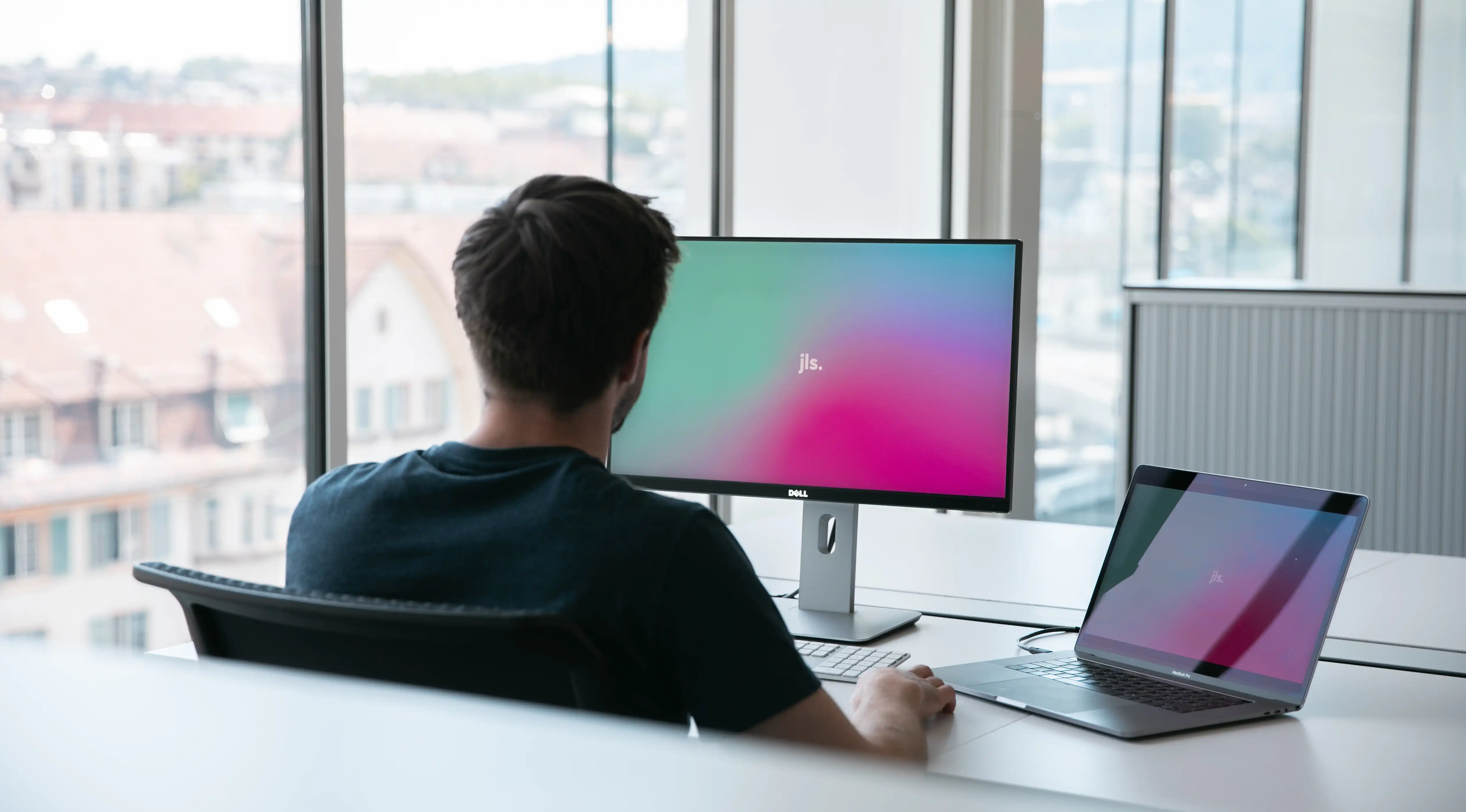 Mann arbeitet mit Macbook und externem Desktop