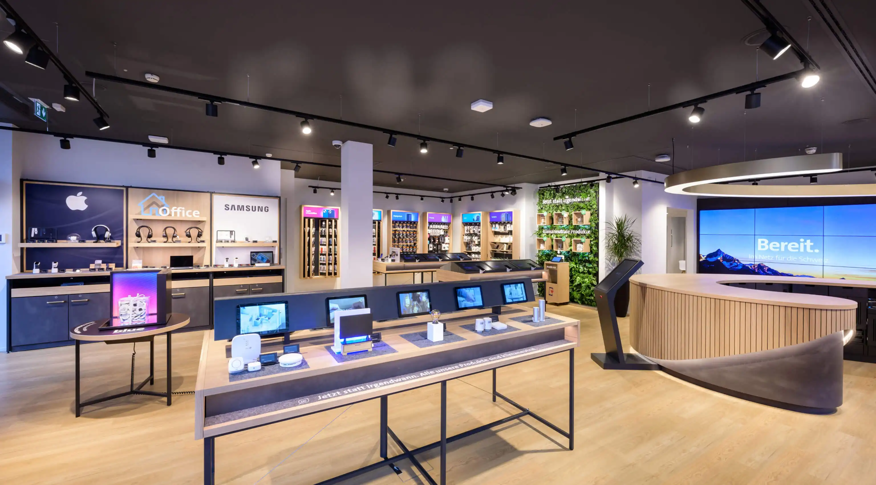 Innenansicht eines Swisscom Shops mit digitalen Displays und Gerätetischen – modernes Retail Design mit LED-Installation am POS in der Schweiz, realisiert von jls.