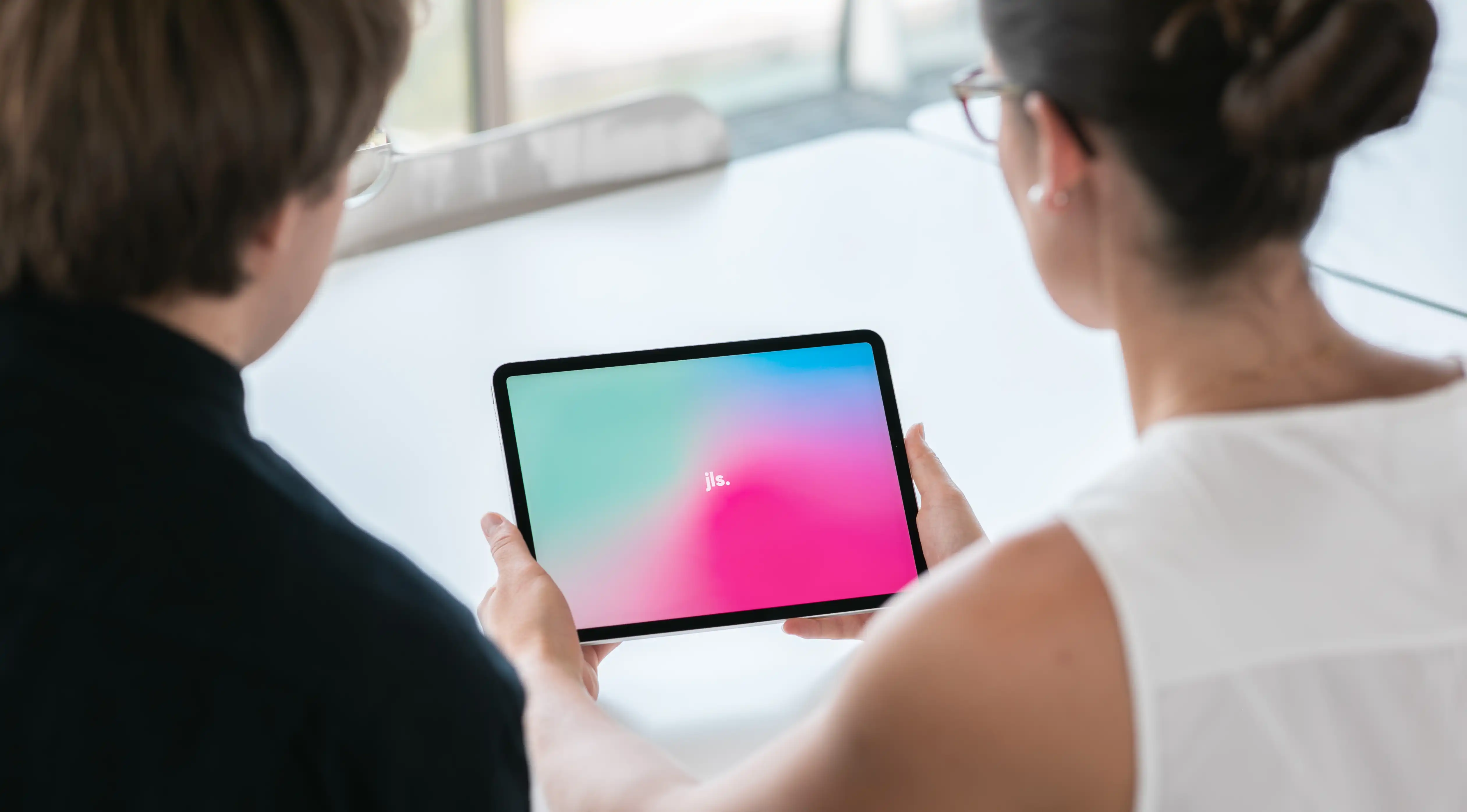 Frau hält Tablet in der Hand, Mann und Frau schauen auf Tablet