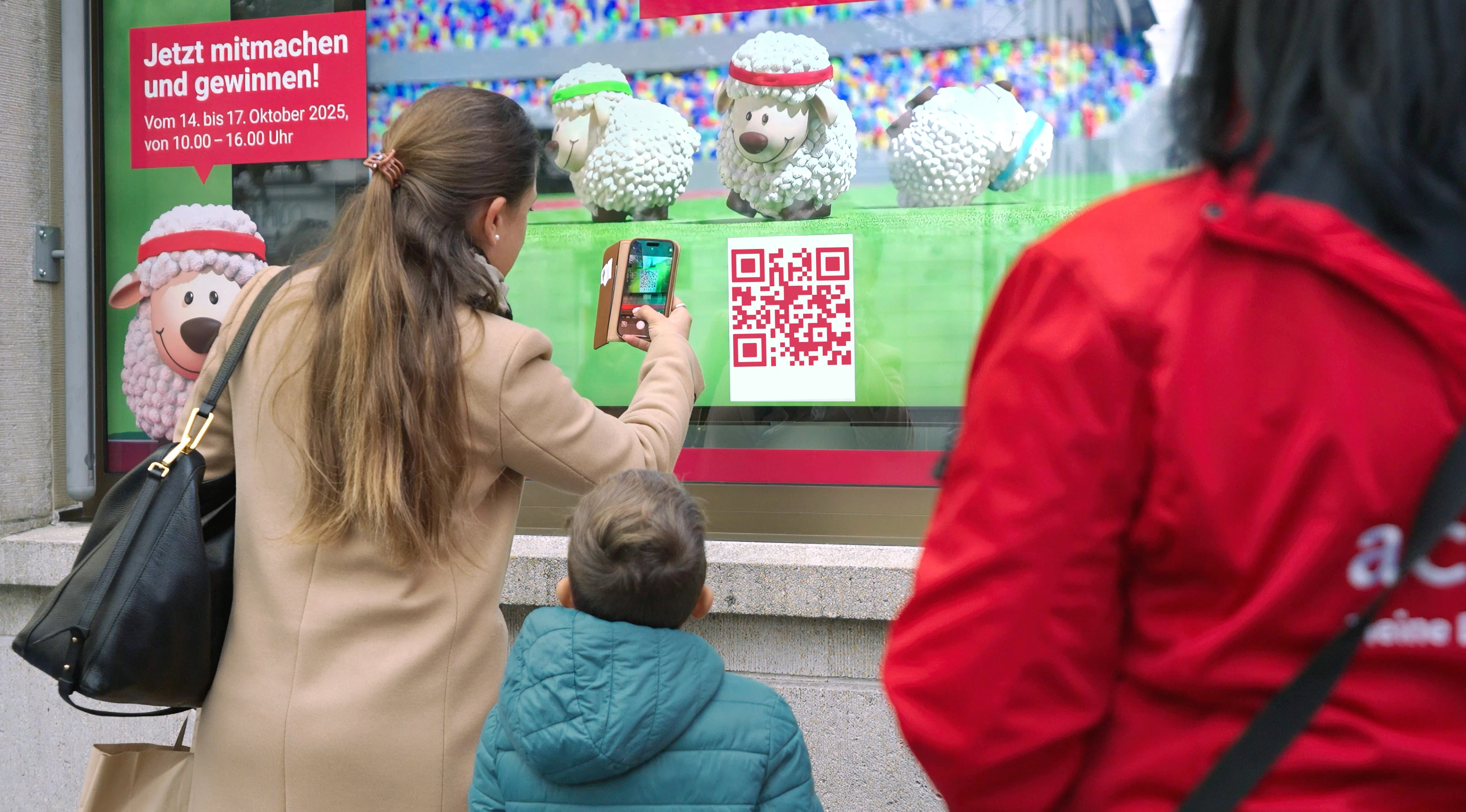 Gamification solution by jls: a woman and child scan a QR code and start the acrevis Miro sheep race on the screen.